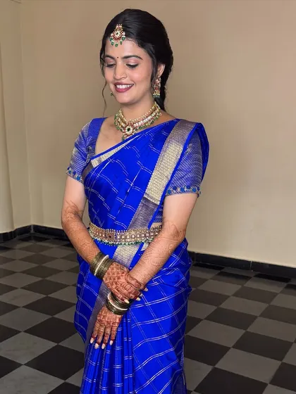 A full view of the bride in her royal blue Mysore silk saree, the drape allowing for easy movement while maintaining its elegance.