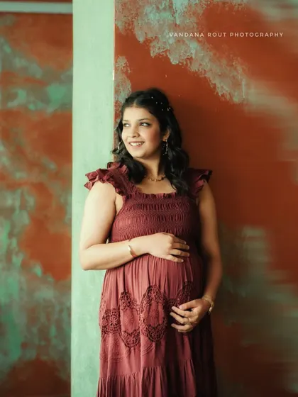 A smiling mother-to-be looks away from the camera in this candid indoor portrait, capturing a moment of happy contemplation.