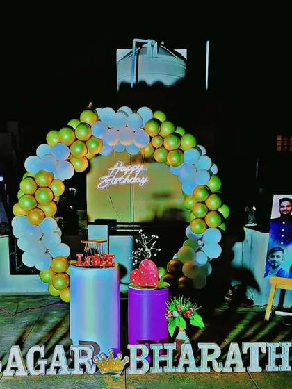 A simple and elegant birthday decoration for a home celebration, featuring a green and gold balloon ring and a personalized photo display.