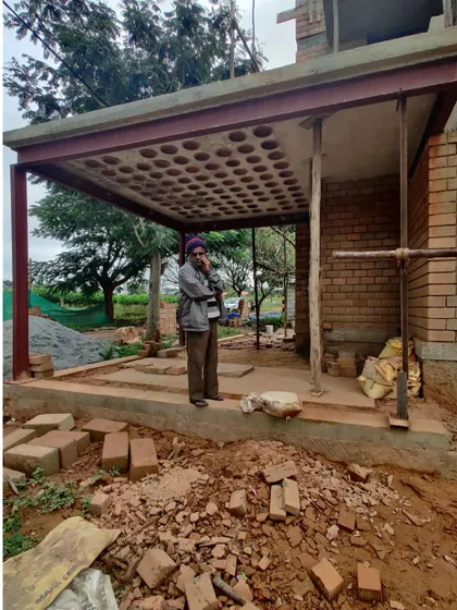 A worker stands under the newly constructed porch with a filler slab roof, a testament to the blend of traditional techniques and modern engineering.