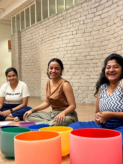 Participants smile, surrounded by colorful crystal singing bowls used for sound healing during our full moon women's circle.