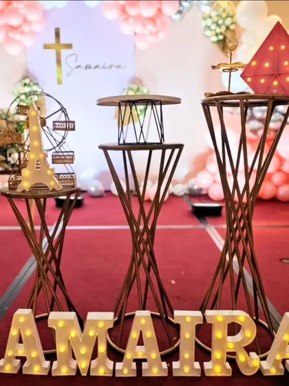 A close-up of the decor details for Samaira's Baptism. We used stylish pedestals to display decorative items like a miniature Eiffel Tower and Ferris wheel, alongside the glowing marquee letters.