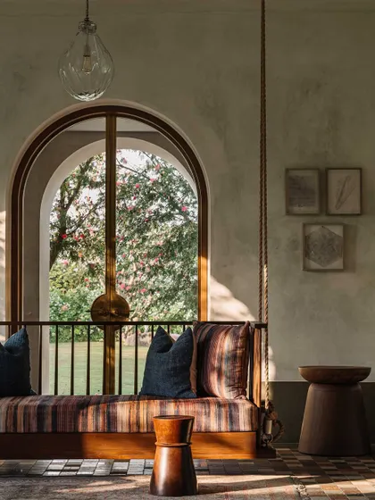 A traditional Indian swing or 'jhula' offers a place for relaxation while looking out onto the garden. This element combines cultural familiarity with modern design, framed by the home's signature arches.