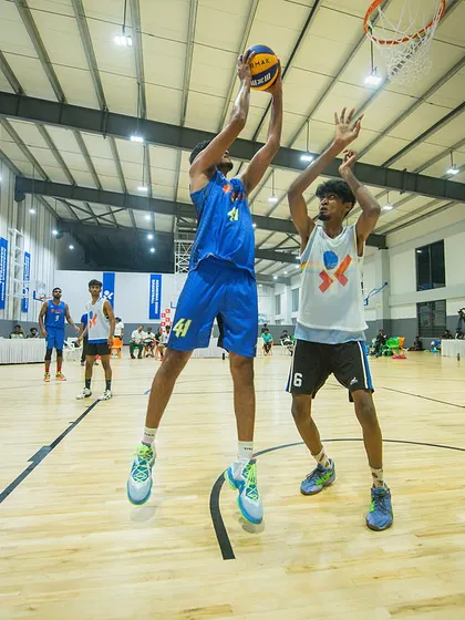 A player elevates for a jump shot over a defender. Early tournament experience sharpens skills and builds character.