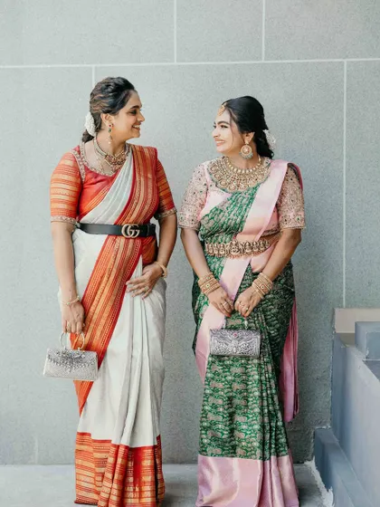 A full-length view of two sisters, showcasing how my custom designs can complement each other. On the left, a modern belted saree, and on the right, a bespoke half-saree.