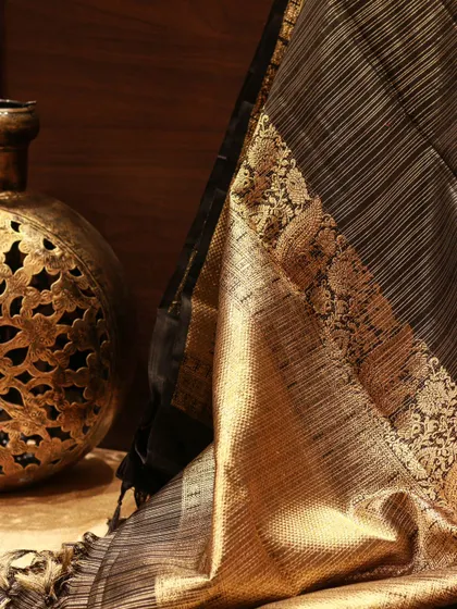 The rich gold pallu of a black Kanjivaram, featuring traditional peacock motifs and intricate border work.