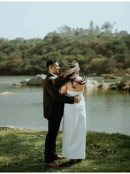 A beautiful shot from behind as the groom holds the bride, her hair blowing in the wind, overlooking the serene lake.