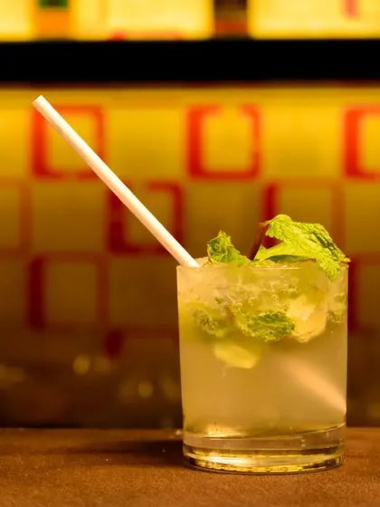 A classic mojito, perfectly styled and lit. This image focuses on the freshness of the mint and the cool, refreshing look of the drink.