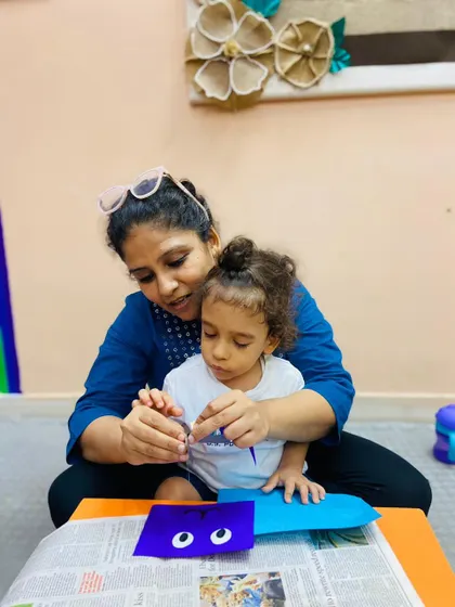 A mother helps her child with a craft, demonstrating the supportive and collaborative nature of our parent-child program.
