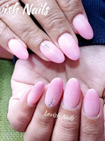 A lovely set of soft pink nails with a "sugar" glitter effect and a few scattered rhinestones for a subtle, textured sparkle.