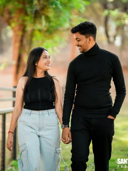 A casual and stylish shot of a couple walking hand-in-hand in a park.