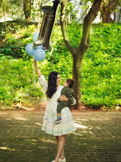 A mother celebrating her son's first birthday. The balloons add a festive touch to this beautiful moment of connection between mother and child.