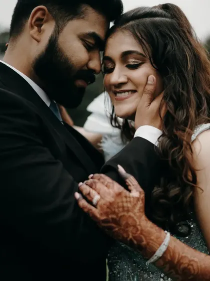 A tender embrace showing his hand on her cheek. The henna on her hand adds a beautiful traditional detail to this romantic engagement photo.