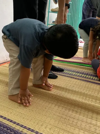 A child practices a forward fold during our yoga session. We introduce yoga through stories and games, making it an enjoyable and accessible practice for our youngest learners.