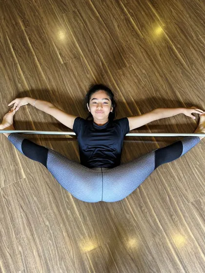 We are all contortionists, bending ourselves to fit. This student demonstrates a perfect middle split on the bar, a result of dedicated flexibility training.
