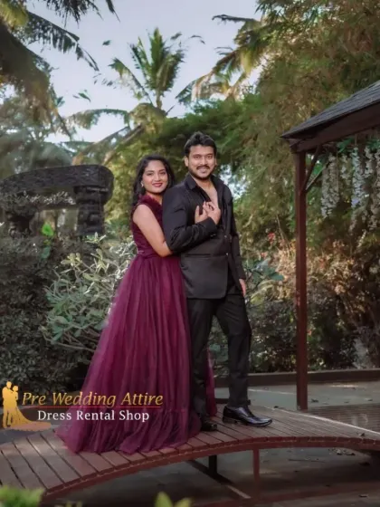 This couple chose a deep maroon gown paired with an all-black suit for a chic and modern look. The outfits are set against a lush green background, making the rich color of the gown pop.