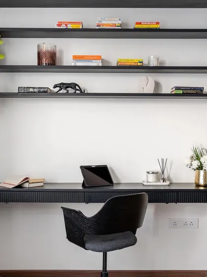 A closer look at a sleek and functional home office. The floating black desk with a fluted front and open shelving above creates a minimalist yet powerful workspace, perfectly organized and ready for inspiration.