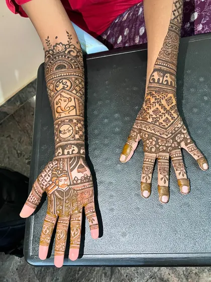 A view of both hands, one with the groom's portrait and the other with a complementary traditional design.