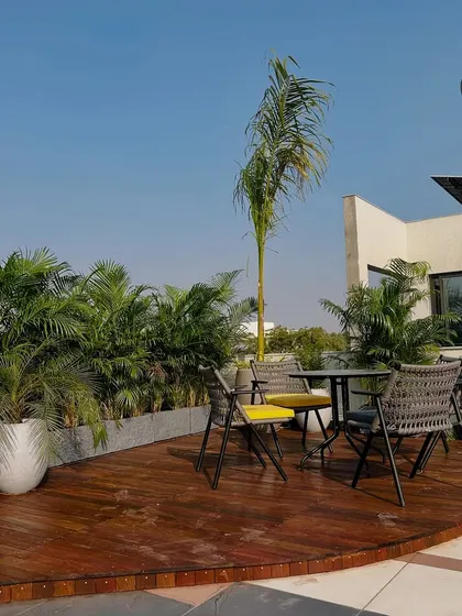 The circular wooden deck creates a defined zone for dining or lounging, separating it from the main terrace area while maintaining an open feel.