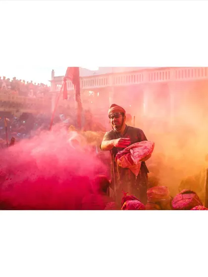 A man prepares to throw a bag of colored powder into the crowd. This is a moment of anticipation just before the explosion of color, showing the energy of the festival.