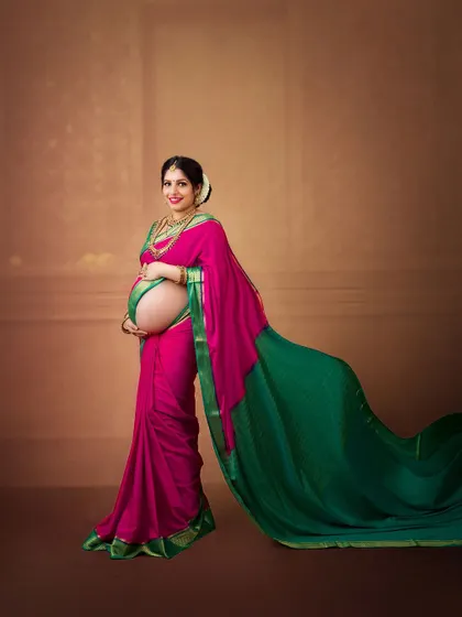 A profile shot that beautifully displays the baby bump under the elegant drape of the saree. The flowing fabric adds a sense of movement and grace.