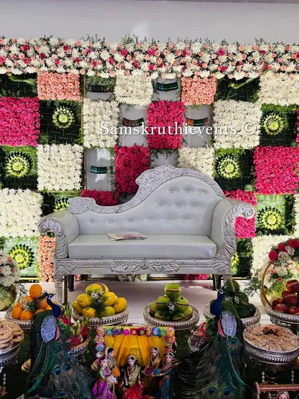 A unique checkered floral backdrop in pink, white, and green. This modern take on traditional patterns, paired with a silver chaise lounge, creates a stylish and elegant setting for a baby shower.