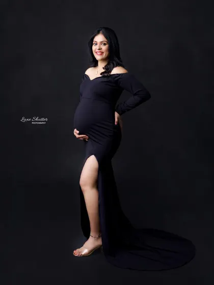 A full-length view of this stunning black maternity gown, perfect for a timeless and classic studio portrait.