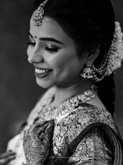 A classic black and white close-up, highlighting the bride's serene smile and the intricate details of her hair and jewelry.