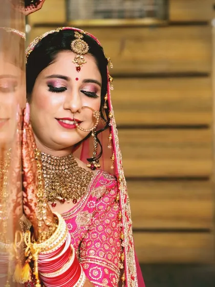 A beautiful close-up of the bride, capturing her flawless makeup and serene expression. The reflection in the pillar adds a creative and artistic touch to the portrait.