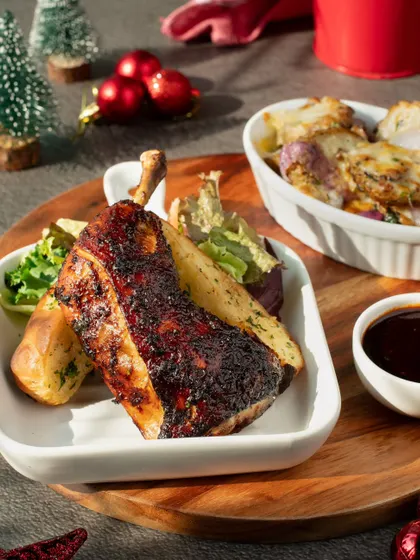 A sophisticated Christmas plate featuring Peruvian chicken and potatoes. The elegant plating and subtle festive decorations make it suitable for a fine-dining holiday menu.