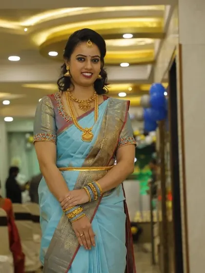 A full-length view of a non-bridal party look. The light blue saree, traditional gold jewellery, and flawless makeup come together for a graceful and polished appearance.