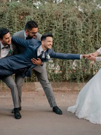 A fun and playful shot of the bride "pulling" her groom away from his groomsmen.