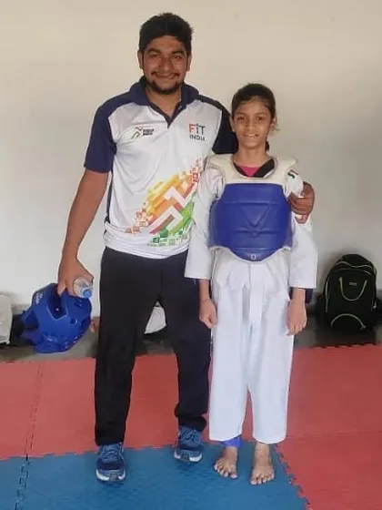 Posing with my student Kinjal Shirke after her gold medal win at the DSO Taekwondo championship. She is wearing her chest guard, ready for the next fight.