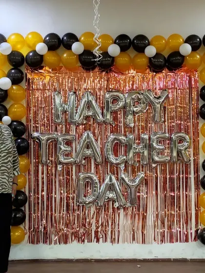 A happy teacher posing in front of the backdrop we created for their special day.
