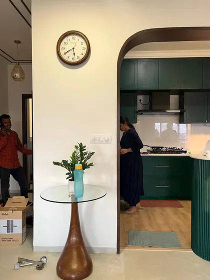 The poetic wall in between. An arched opening frames the view into a deep green kitchen, creating a beautiful transition between spaces.