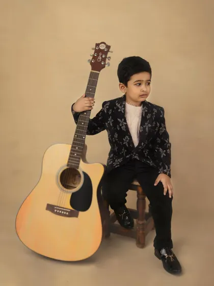 A thoughtful, candid moment from the guitar session. The boy looks off-camera, creating a portrait that feels natural and introspective.