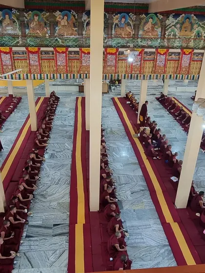 The expansive prayer hall at Sera Jey, with its beautiful thangkas and rows of dedicated monks, during the formal Geshe ceremony. The scale of the gathering reflects the significance of the event.