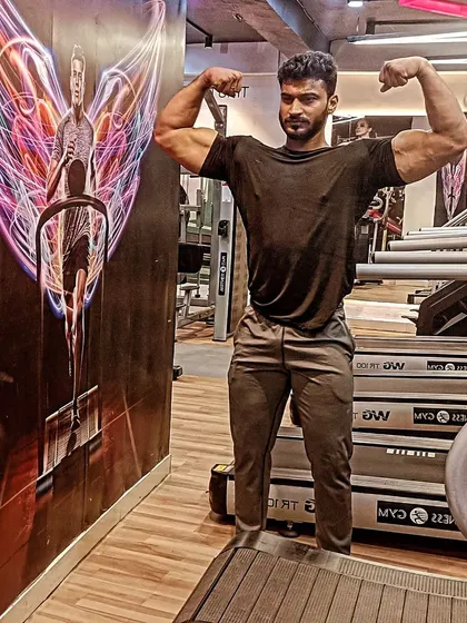 Gains over brains. A double biceps pose near the treadmills.