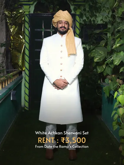 A classic white achkan sherwani set. This timeless piece is perfect for a groom who wants a regal and elegant look.