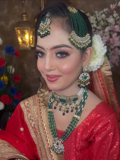 A close-up of the exquisite jewellery. The green beaded passa and maang tikka are paired with a matching choker and a longer necklace, creating a layered and royal effect.
