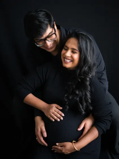 A happy, candid moment during a couples maternity shoot. The genuine smiles and easy connection between them make this a heartwarming portrait.