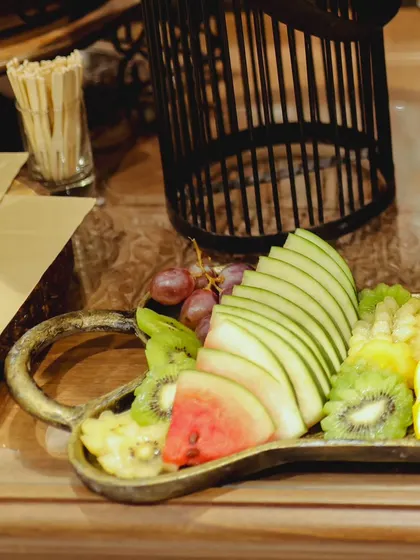 Detail shot of our meticulously sliced fruit platter, showcasing fresh apples, kiwi, watermelon, and oranges. We focus on presentation to make even the simplest offerings look exquisite.