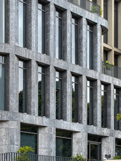 A detailed shot of the Afyon Grey marble facade, showing the rhythmic pattern of windows and cladding. The consistency and precision in the joinery reflect our commitment to high-quality execution in commercial construction.