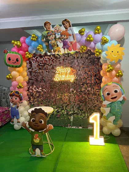 Another view of the Cocomelon first birthday, showing the full setup with the shimmer wall and green turf floor.