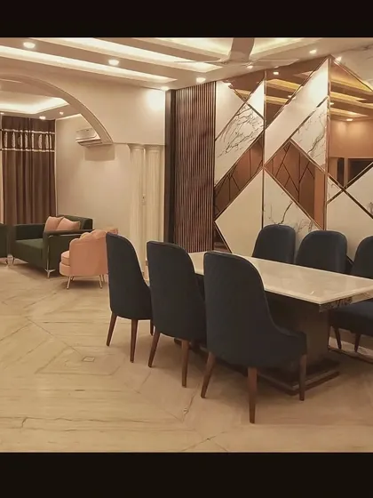 This image shows the dining area adjacent to the living room from our quick renovation project, tied together by a striking geometric wall panel of marble and mirror.