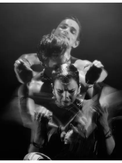 A black and white photo capturing a moment of conflict and connection in 'Naga Mandala'. The motion blur adds to the dynamic energy of the scene.