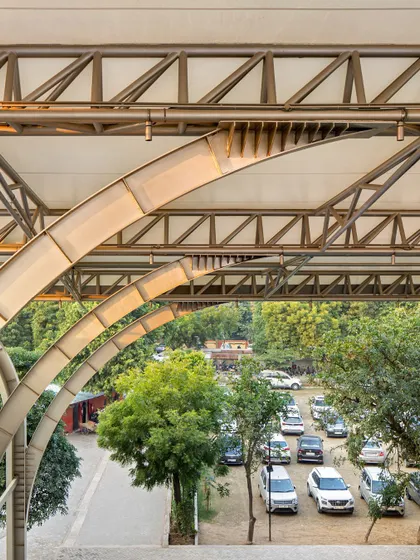 The canopy structure frames the view of the surrounding landscape and parking area, showing how the new addition integrates with the broader campus environment.