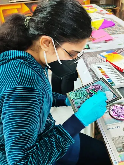 A close-up of a student creating a relief artwork. Our workshops cover various techniques for building up layers and creating intricate textures with clay.