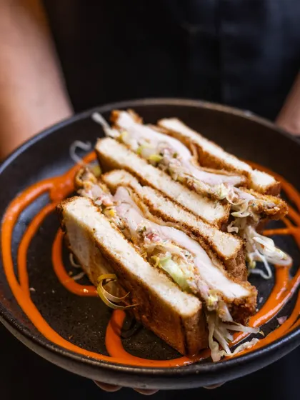 Another look at the iconic Buttermilk Fried Chicken Sandwich, held up and ready to be enjoyed. The layers of chicken, sauce, and bread are perfectly balanced.