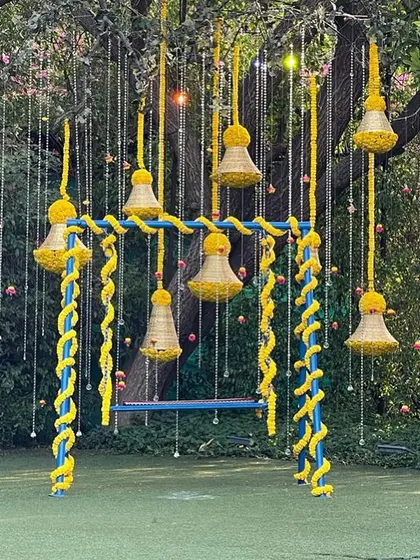 A playful swing decorated with marigold strings and bells, a perfect, interactive photo corner for a Mehendi or Haldi ceremony.